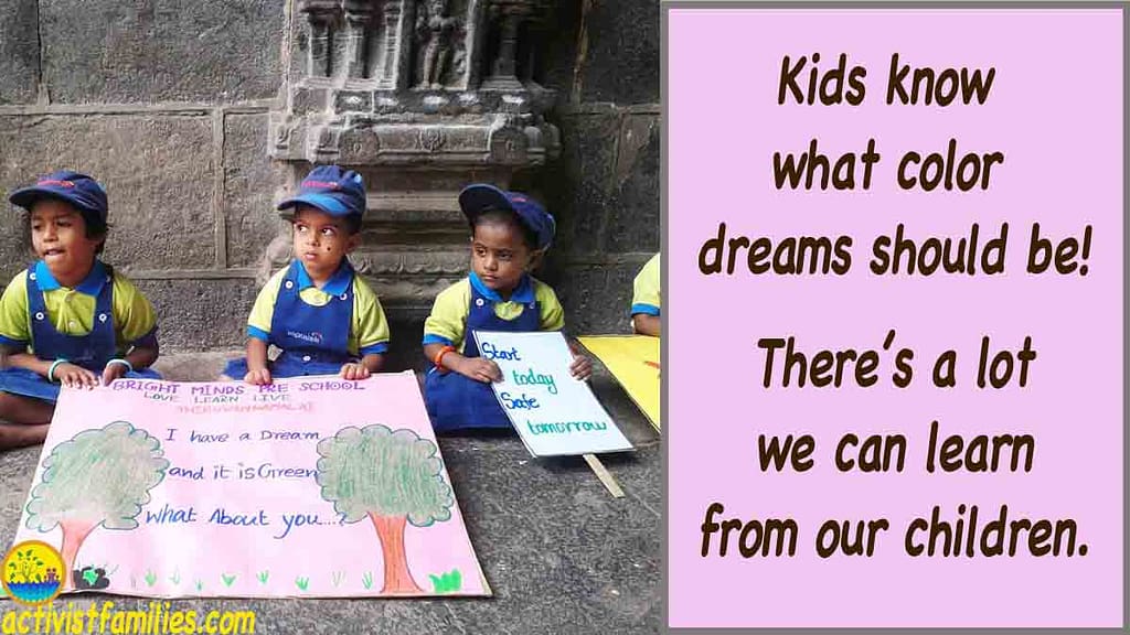 Three pre-school boys sit on the floor listening to someone, holding signs they’ve painted for an eco-event. One large sign shows drawings of trees and flowers and the words, “I have a dream, and it is green. What about you?” Another sign says, “Start today, safe tomorrow.” Large text to the right of the picture says, “Kids know what color dreams should be!” Great signs for kids without mentioning global warming.