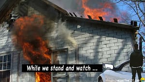 A man stands and watches as his home burns. Words say, "While we stand and watch ..."