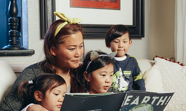 Asian family reading a children's book about the Earth together
